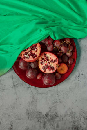 plums, pomegranate and grapes covered in green in a grey stone backgroundの写真素材