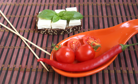 Fresh cherry tomatoes and chili on red plate.の写真素材