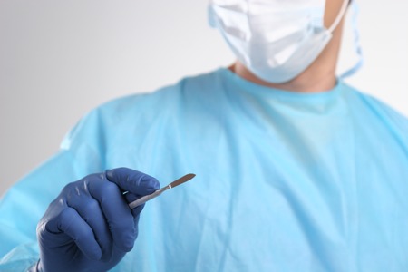 Male doctor in blue surgeon holds a scalpel.の写真素材