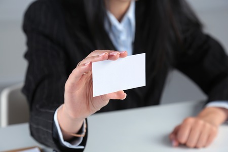 Businesswoman holding blank visit card ,sitting on the deskの写真素材