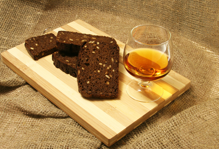 A glass whiskey and slices of bread on a wooden board.の写真素材