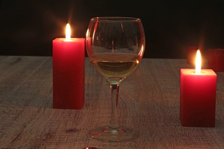 glass of wine or cognac and red candle on a wooden background.の写真素材