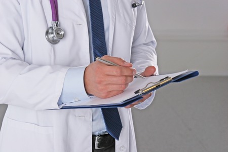 Male doctor standing with folder, isolated on white backgroundの写真素材