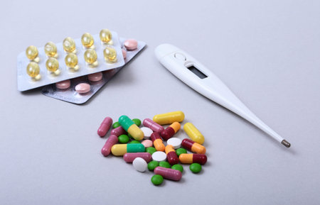 Pills and medical thermometer on white background. .