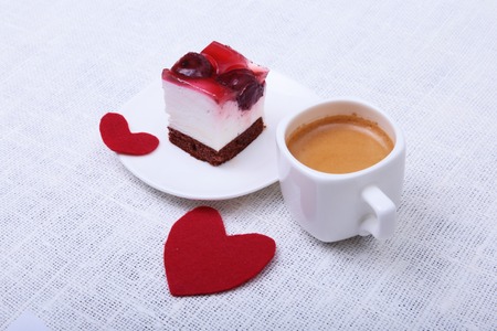 Close-up of white cup of coffee and strawberry cake. Red heart valentines day.の写真素材