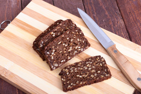 Sliced black bread and knife on the old wooden plank