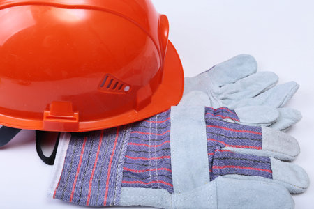 Orange hard hat, safety glasses, gloves and measuring tape on white isolated