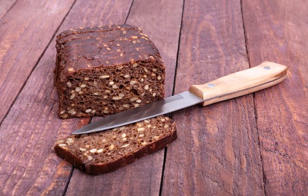 Assorted fresh breads, slice and knife isolated on old wood table.の写真素材