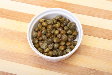 bowl with fresh capers on wooden tableの写真素材