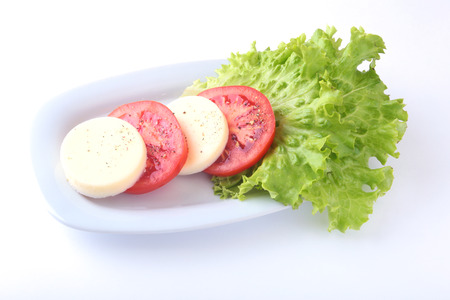 Portion of Mozzarella with Tomatoes, lettuce leaf and Balsamic dressing on white plate. selective focus close-up shot.の写真素材