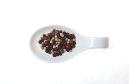 mixed black, white and red pepper corns in bowl isolated on white background.