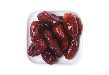 Delicious dried organic dates on bowl isolated over white background.