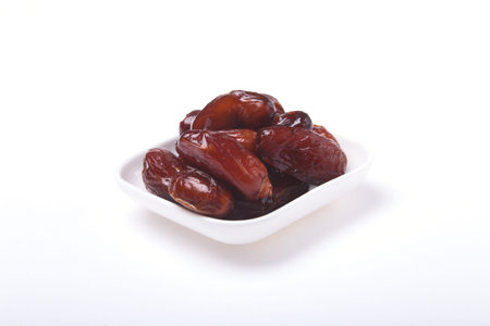 Delicious dried organic dates on bowl isolated over white background.
