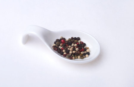 mixed black, white and red pepper corns in bowl isolated on white background.