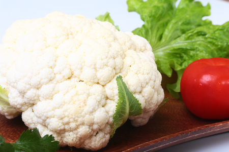 fresh cauliflower, tomato, salad leaves and other vegetables on wooden board. Ready for cooking. Vegetarian food.の写真素材