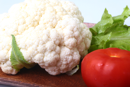 fresh cauliflower, tomato, salad leaves and other vegetables on wooden board. Ready for cooking. Vegetarian food.の写真素材