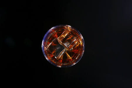 Glass of whiskey or bourbon with ice on black stone table. Top view.の写真素材