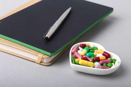 notebook and colorful assortment pills, capsules on plateの写真素材
