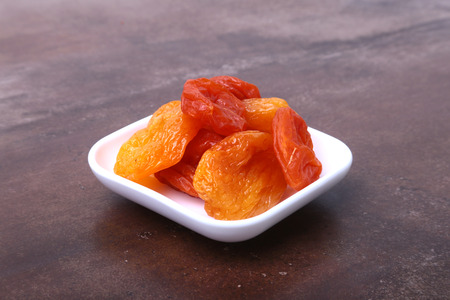Delicious dried organic apricots in bowl isolated on stone table.の写真素材