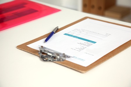 Closeup of white desktop with notepads, pen, coffee cup and other items. Selective focus.の写真素材