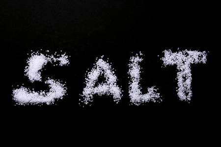 White sea salt isolated on a black background. Selective focus.の写真素材