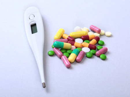 Pills and medical thermometer on white background. .の写真素材