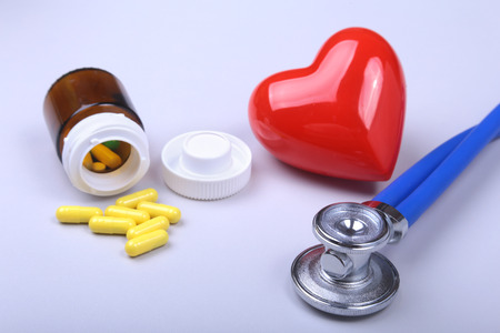 Stethoscope, red heart and assorted pills on white table with space for text.の写真素材