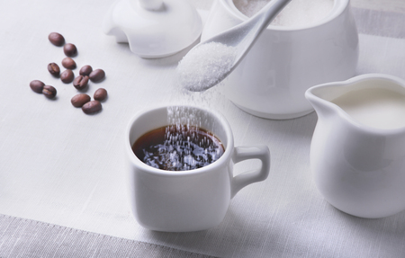 Cup of hot coffee espresso, coffee beans, jug of milk, and bowl with sugar on white background for copy space. Coffee concept.の写真素材
