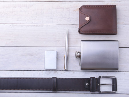 Gadgets and accessories for men on light wooden background. Fashionable men s belt, wallet, lighter,...