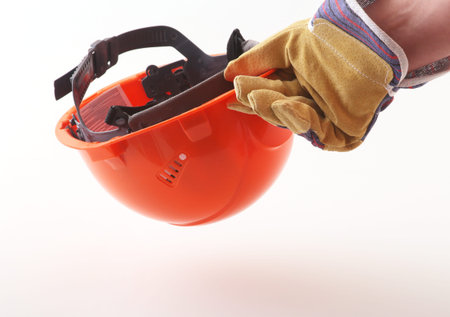 worker in protective gloves holds an orange hard hat in his hand. Safety helmet.