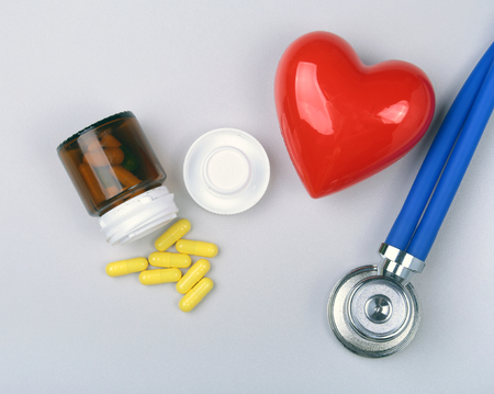 Stethoscope, red heart and assorted pills on white table with space for text.の写真素材
