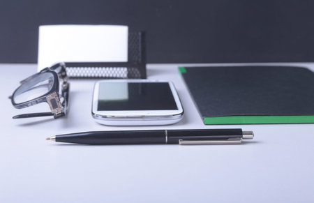 Business concept. Top view of kraft spiral notebook, glasses, smartphone and black pen isolated on...