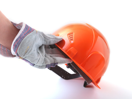 worker in protective gloves holds an orange hard hat in his hand. Safety helmet.の写真素材