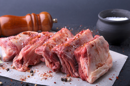 Raw fresh meat, uncooked lamb or beef ribs with pepper, garlic, salt, bay leaves and spices on dark stone background, Ready for cooking. copy space.の写真素材