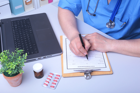 Close-up view of female doctors hands filling patient registration or prescription form. Health care, medical and pharmacy concept.の写真素材
