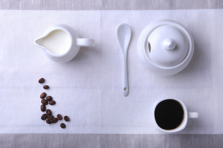 Cup of hot coffee espresso, coffee beans, jug of milk, and bowl with sugar on white background for copy space. Coffee concept.の写真素材