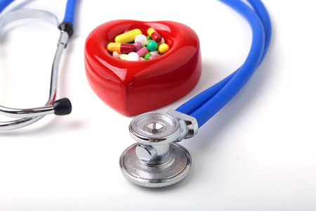 Red heart, asorted pils and a stethoscope on white background.の写真素材