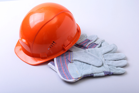 Orange hard hat, goggles and safety gloves on a white background.の写真素材