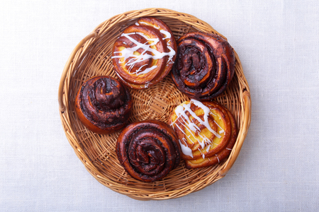 Freshly baked homemade sweet bun or sweet rolls with cinnamon in a wicker basket.の写真素材