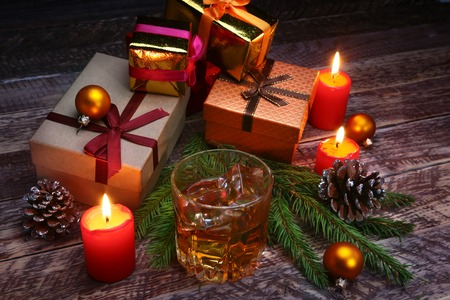 Glass with cognac or whiskey, Christmas balls and candles. New Years tree, balls and glass with alcohol.の写真素材