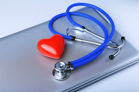 Workplace of doctor with stethoscope, red heart, laptop, rx prescription and notebook on white table. top view.の写真素材