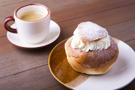 Swedish Semla, traditional Shrove bun, consists of light wheat bread with almond paste and whipped cream filling. cup with coffee.の写真素材