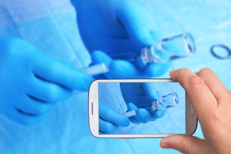 hands of man with smartphone taking photo Syringe, ampule in hand, palm or fingers. Medicine plastic...