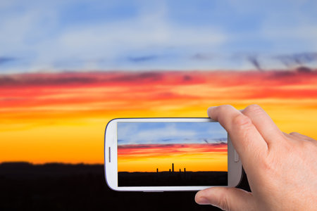 hands of man with smartphone taking photo Industrial panorama on the background of a colorful...
