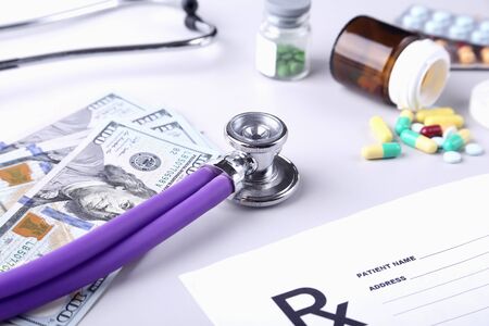 Bottle of pills, dollars banknotes and stethoscope lying on cardiogram chart closeup.の写真素材