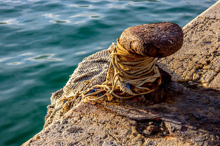 Old mooring bollard with rope on the quayの写真素材