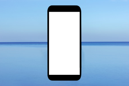 A mobile phone with the blue sea in the backgroundの写真素材