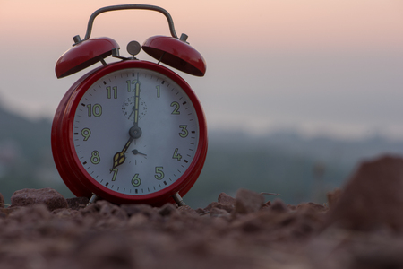 A Red alarm clock at sunrise on the mountainの写真素材
