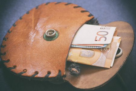 An old purse of brown color with money insideの写真素材