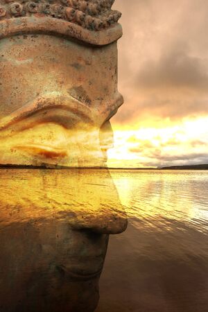 Figure of a Buddha with a lake at sunrise in the background, Spainの写真素材